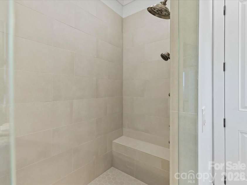 18014 Whispering Oaks Drive, Cornelius, NC 28031.  MLS# CAR4356897, YatesRealty ID 16097. Oversized tiled walk-in shower with frameless glass enclosure, built-in bench seating, and dual showerheads creates a luxurious spa-like experience.