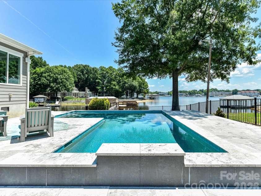 18014 Whispering Oaks Drive, Cornelius, NC 28031.  MLS# CAR4356897, YatesRealty ID 16097. Resort-style pool with expansive sun deck overlooks beautiful Lake Norman, creating the perfect setting for relaxation, entertaining, and enjoying breathtaking waterfront views.