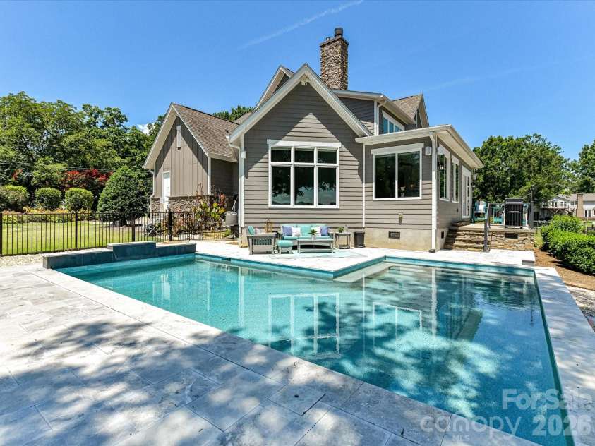 18014 Whispering Oaks Drive, Cornelius, NC 28031.  MLS# CAR4356897, YatesRealty ID 16097. Resort-style saltwater pool with expansive travertine decking creates a stunning outdoor retreat overlooking serene waterfront views, perfect for relaxing and entertaining.