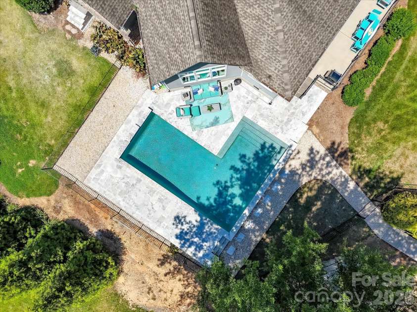 18014 Whispering Oaks Drive, Cornelius, NC 28031.  MLS# CAR4356897, YatesRealty ID 16097. Resort-style saltwater pool with expansive travertine decking creates a stunning outdoor retreat overlooking serene waterfront views, perfect for relaxing and entertaining.