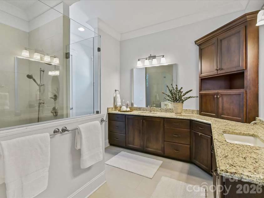 18014 Whispering Oaks Drive, Cornelius, NC 28031.  MLS# CAR4356897, YatesRealty ID 16097. Spa-inspired primary bath features dual granite vanities, a spacious tiled walk-in shower, abundant cabinetry, and generous counter space for everyday luxury.