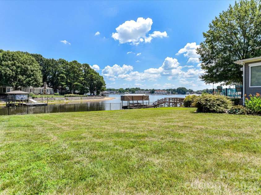 18014 Whispering Oaks Drive, Cornelius, NC 28031.  MLS# CAR4356897, YatesRealty ID 16097. The expansive, level backyard offers plenty of space for recreation, entertaining, and enjoying peaceful lake views in a beautifully landscaped setting.