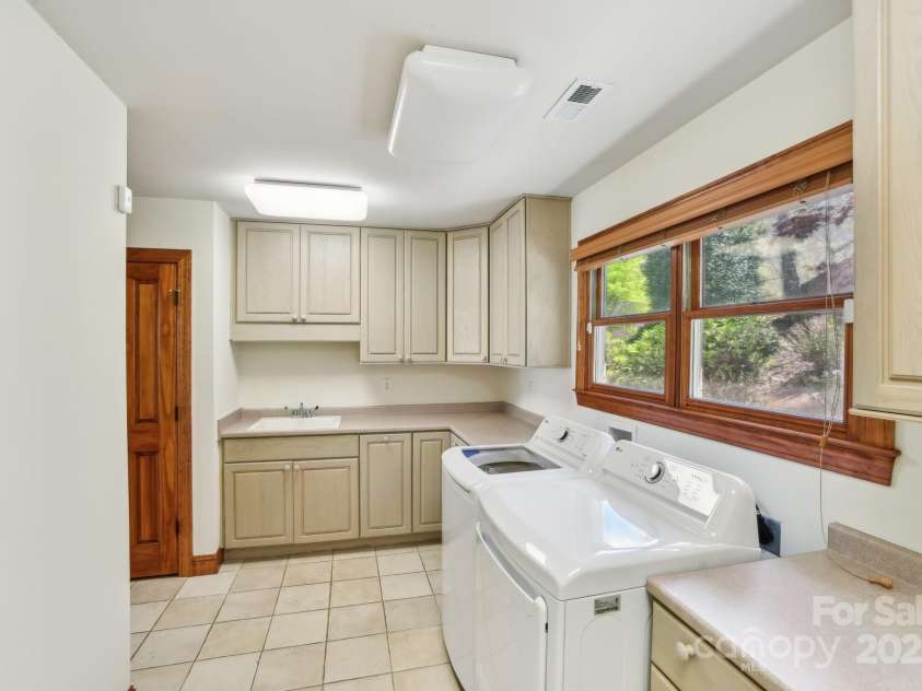 206 View Ridge Parkway, Leicester, NC 28748.  MLS# CAR4228261, YatesRealty ID 16135. Bright and functional laundry room featuring windows, ample storage space, and a convenient sink for added practicality