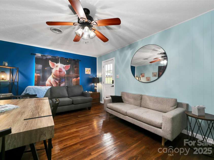 626 Fairview Loop, Hot Springs, NC 28743.  MLS# CAR4302454, YatesRealty ID 1621. Living Room, decorated with piggies, looking back toward the front door out to the front porch. The middle bedroom is alive with bunny rabbits in every corner! Light and bright with beautiful oak hardwood floors.