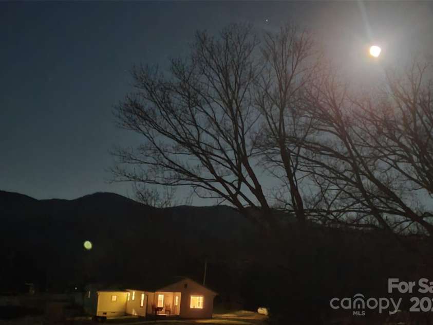 626 Fairview Loop, Hot Springs, NC 28743.  MLS# CAR4302454, YatesRealty ID 1621. The house under a full moon in winter, with the mountain range to the east.
