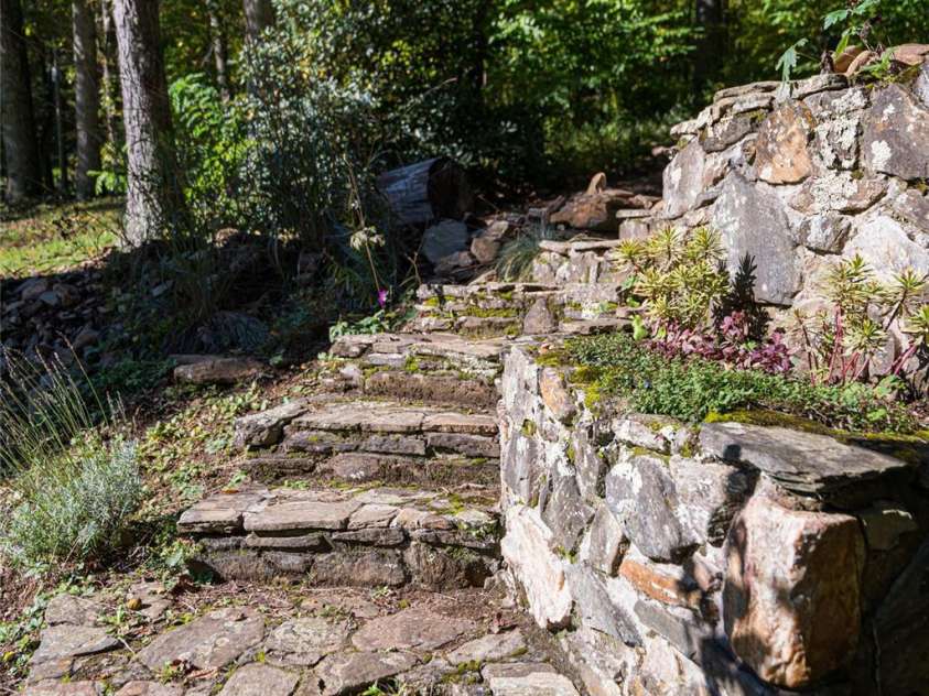 360 Banjo Branch Road, Burnsville, NC 28714.  MLS# CAR4310323, YatesRealty ID 1637. There are stone stairs leading down to the unfinished basement below the A-Frame home 