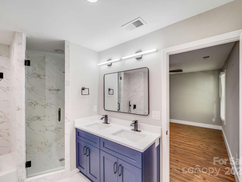 2000 Tyvola Road, Charlotte, NC 28210.  MLS# CAR4260481, YatesRealty ID 16600. A private en-suite bath adorned with high-end finishes, including quartz countertops, custom tile work, tiled tub surrounds, and frameless glass showers—offering a spa-like retreat right at home.