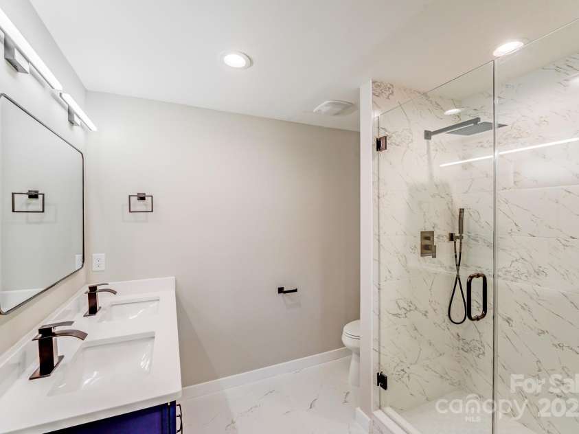2000 Tyvola Road, Charlotte, NC 28210.  MLS# CAR4260481, YatesRealty ID 16600. A private en-suite bath adorned with high-end finishes, including quartz countertops, custom tile work, and frameless glass showers—offering a spa-like retreat right at home.