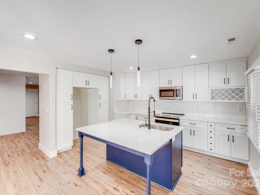 2000 Tyvola Road, Charlotte, NC 28210.  MLS# CAR4260481, YatesRealty ID 16600. This open-concept kitchen welcomes you with a graciously sized bar, perfect for casual dining and entertaining. Crisp white shaker-style cabinets add timeless charm, while the seamless flow draws you into a breathtaking a