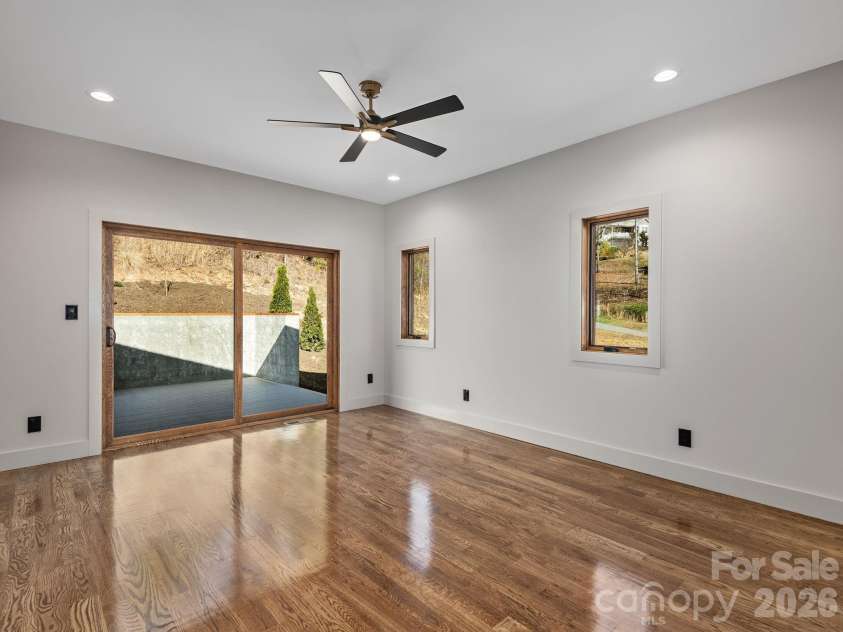 48 Verde Drive, Asheville, NC 28806.  MLS# CAR4364556, YatesRealty ID 16757. Representative photo from 50 Verde Drive showing the builder’s quality of construction and finish level, including a primary bedroom with oak hardwood floors, ensuite bath, and large sliding doors opening to the rear deck.