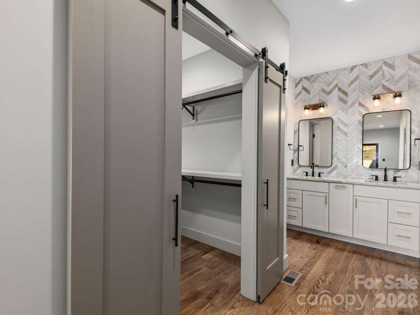 48 Verde Drive, Asheville, NC 28806.  MLS# CAR4364556, YatesRealty ID 16757. Representative photo from 50 Verde Drive showing the builder’s quality of construction and finish level, including a primary ensuite with spacious walk-in closet, wood shelving, sliding barn doors, Wolf cabinetry, granite c