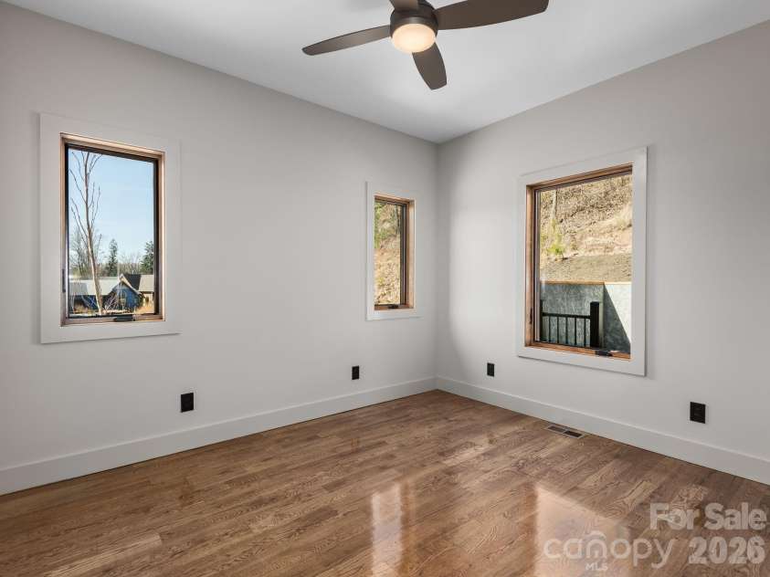 48 Verde Drive, Asheville, NC 28806.  MLS# CAR4364556, YatesRealty ID 16757. Representative photo from 50 Verde Drive showing the builder’s quality of construction and finish level, including a secondary bedroom with oak hardwood floors, ceiling fan, and abundant natural light.