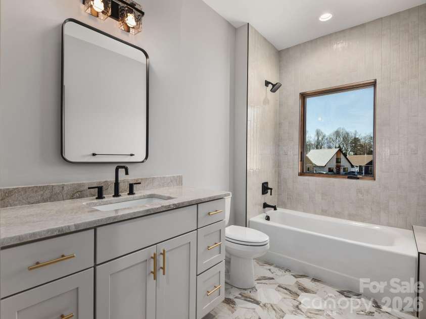 48 Verde Drive, Asheville, NC 28806.  MLS# CAR4364556, YatesRealty ID 16757. Representative photo from 50 Verde Drive showing the builder’s quality of construction and finish level, including a secondary full bath with granite countertop, Wolf cabinetry, designer mirror and lighting, ceramic tile fl