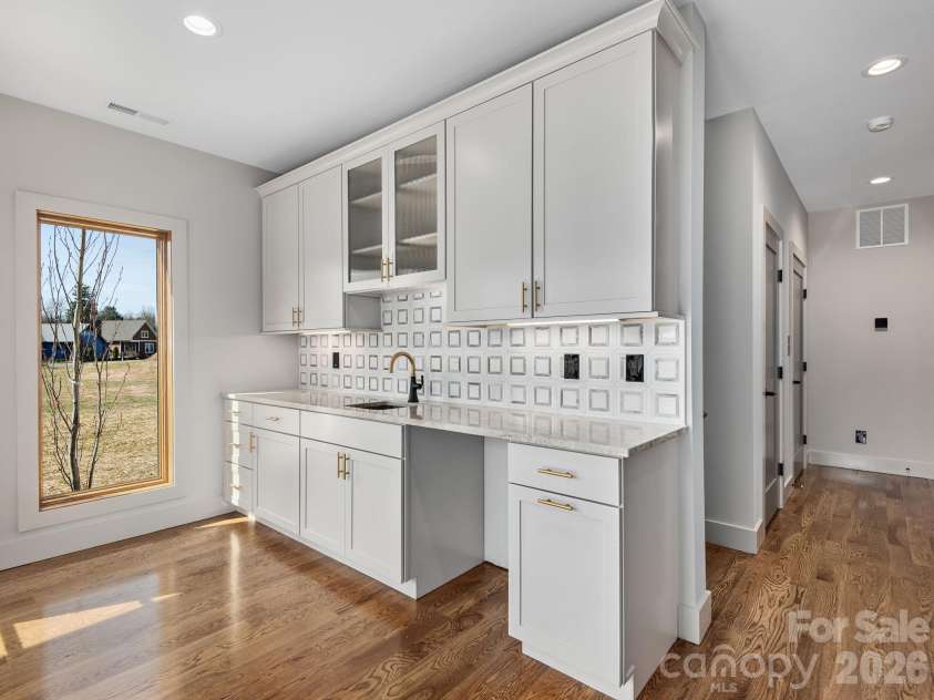 48 Verde Drive, Asheville, NC 28806.  MLS# CAR4364556, YatesRealty ID 16757. Representative photo from 50 Verde Drive showing the builder’s quality of construction and finish level, including the lower-level entrance foyer with oak hardwood floors, Wolf cabinetry with sink, granite countertop, decor