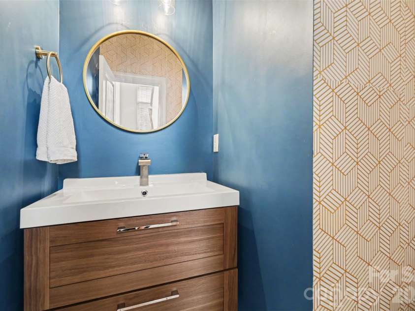 2729 Avalon Loop Road, Charlotte, NC 28269.  MLS# CAR4366095, YatesRealty ID 16859. Convenient main-level half bath featuring a modern vanity, fresh paint, and a stylish geometric accent wall.