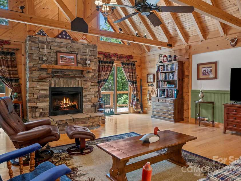 23 Jay Foster Way, Saluda, NC 28773.  MLS# CAR4278065, YatesRealty ID 1689. Inviting gas log fireplace (unvented) composed of cultured stone, custom mantel carved with bear and Mountain profile, & raised hearth.  Track lighting shows off the detail of the trusses and tongue and groove ceiling.