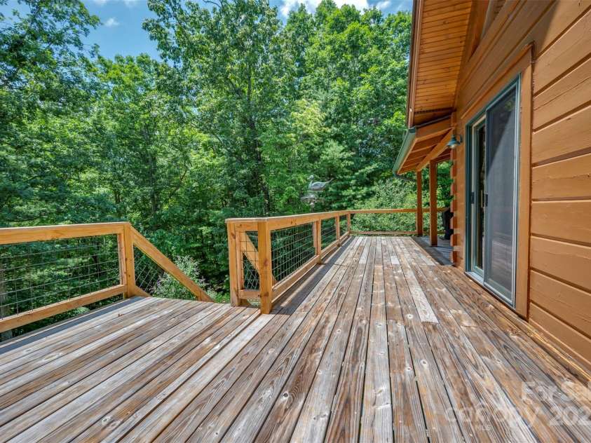 23 Jay Foster Way, Saluda, NC 28773.  MLS# CAR4278065, YatesRealty ID 1689. Rear deck, with hog wire railing, is surrounded by woods and extremely private!   Stairs lead to fenced area outside of basement patio for pets and/or children.