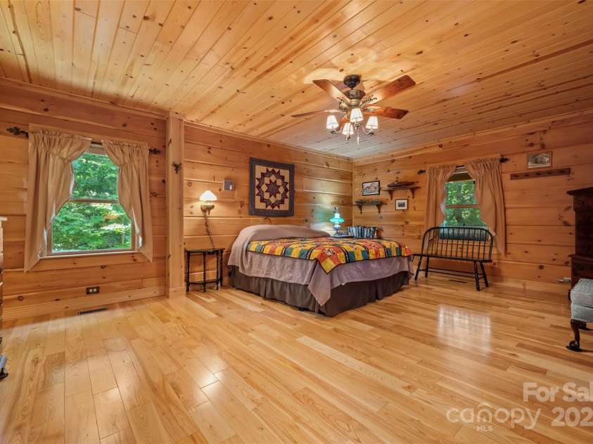 23 Jay Foster Way, Saluda, NC 28773.  MLS# CAR4278065, YatesRealty ID 1689. YES, that IS a sizeable primary bedroom!  En-suite bath to the left. (LAMP ON WALL & COATRACK DO NOT CONVEY, REMOVED!)