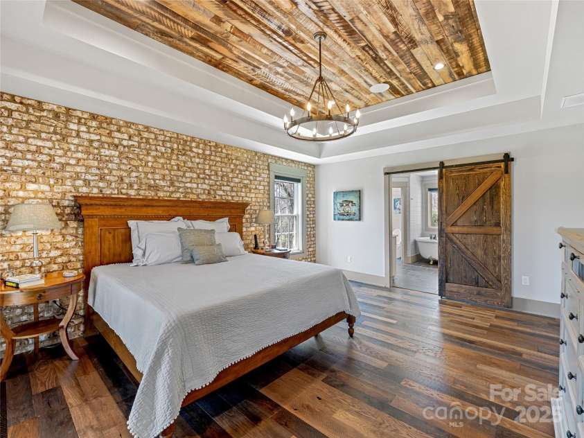 59 Bradford Hill Road, Mills River, NC 28759.  MLS# CAR4241459, YatesRealty ID 16892. Primary bedroom suite with brick accent wall and tray ceiling