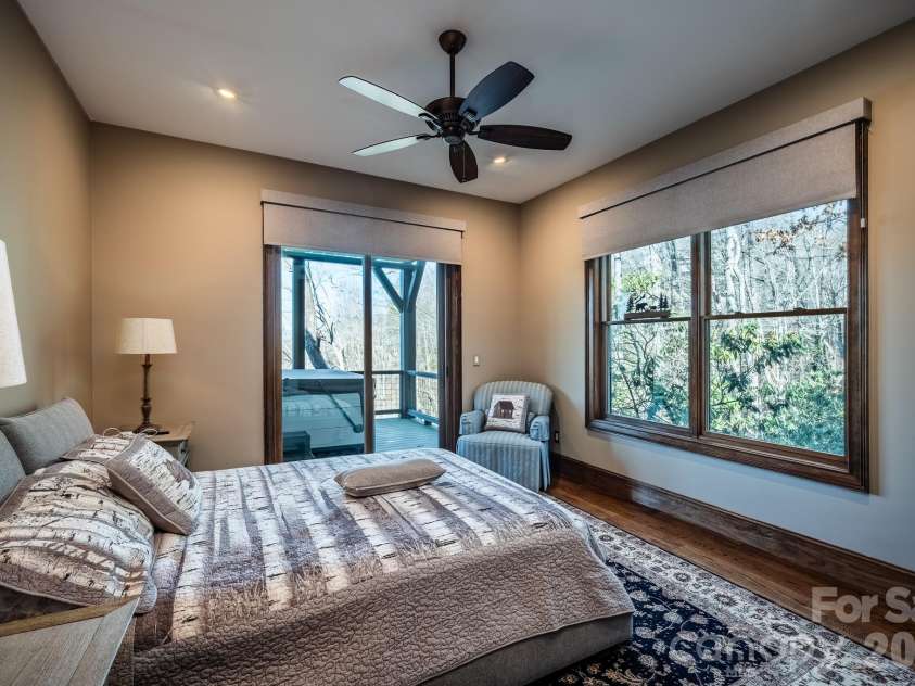 333 Kanasdatsi Drive, Brevard, NC 28712.  MLS# CAR4330137, YatesRealty ID 16902. Bedroom with Private Deck Access to Hot TubSpacious bedroom featuring hardwood floors, neutral tones, ceiling fan, and large windows that bring in natural light. Sliding glass door provides direct access to the covered 