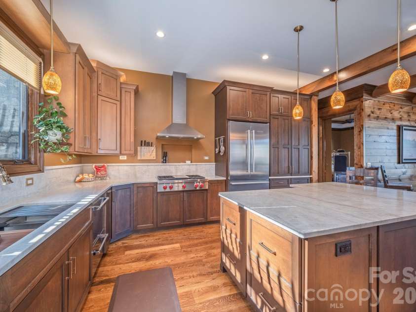 333 Kanasdatsi Drive, Brevard, NC 28712.  MLS# CAR4330137, YatesRealty ID 16902. Chef’s kitchen with custom wood cabinetry, oversized stone island, premium stainless appliances, and warm pendant lighting—designed for both everyday function and entertaining.