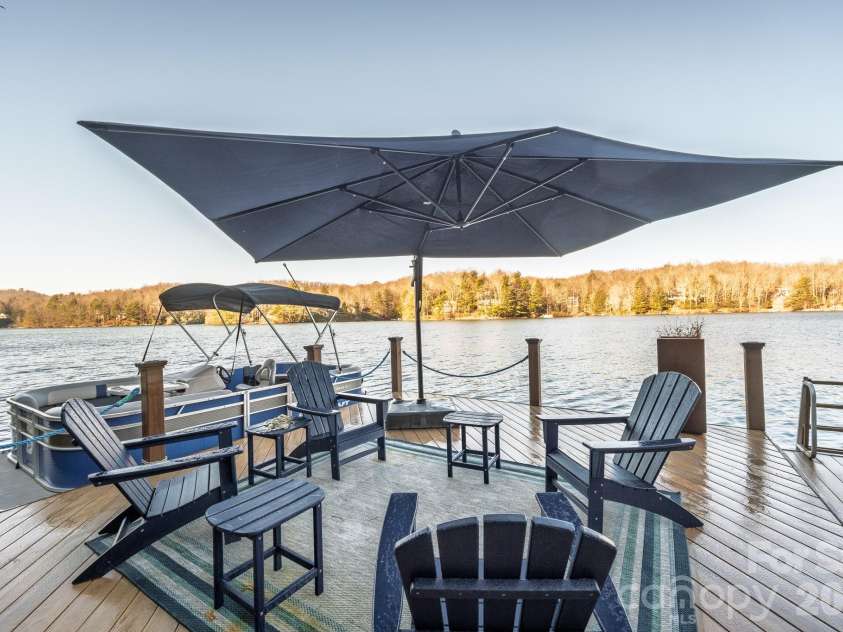 333 Kanasdatsi Drive, Brevard, NC 28712.  MLS# CAR4330137, YatesRealty ID 16902. Dock seating area with Adirondack chairs, umbrella, and pontoon boat, perfect for relaxing and enjoying lake views. Fish and swim from dock or from the included pontoon boat