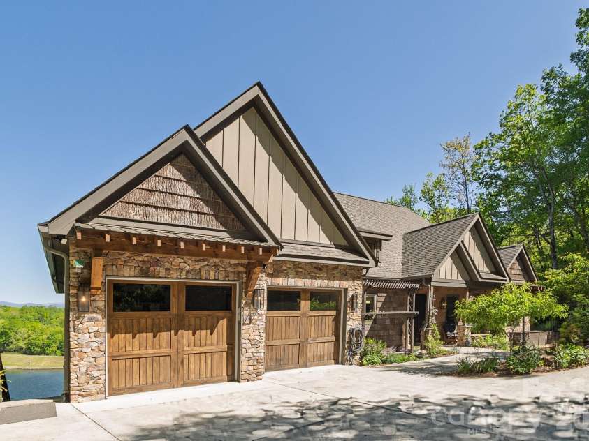 333 Kanasdatsi Drive, Brevard, NC 28712.  MLS# CAR4330137, YatesRealty ID 16902.  Front Exterior with Two-Car Garage, Custom Wood Doors &  Quality Craftsmanship Native Stonework. Mountain-inspired design create a grand yet welcoming arrival experience. Bark wood and Low Maintenance Siding