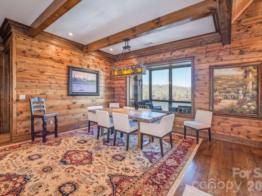 333 Kanasdatsi Drive, Brevard, NC 28712.  MLS# CAR4330137, YatesRealty ID 16902. Inviting and well-scaled dining space highlighted by rich wood-encased walls and exposed beams, complemented by year-round lake and mountain views for an exceptional dining setting.
