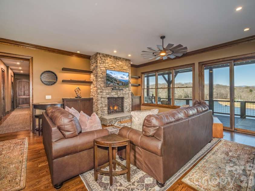 333 Kanasdatsi Drive, Brevard, NC 28712.  MLS# CAR4330137, YatesRealty ID 16902. Lower-Level Family Room with Stone Fireplace & Deck AccessInviting lower-level family room featuring a floor-to-ceiling stone fireplace, custom built-ins, rich hardwood floors, recessed lighting, and a modern ceiling fa
