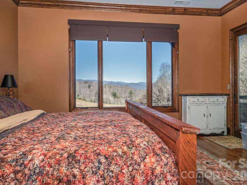 333 Kanasdatsi Drive, Brevard, NC 28712.  MLS# CAR4330137, YatesRealty ID 16902. Primary bedroom featuring warm wood tones, large picture windows, and tranquil mountain views creating a peaceful retreat. (primary bedroom, mountain views, luxury cabin)