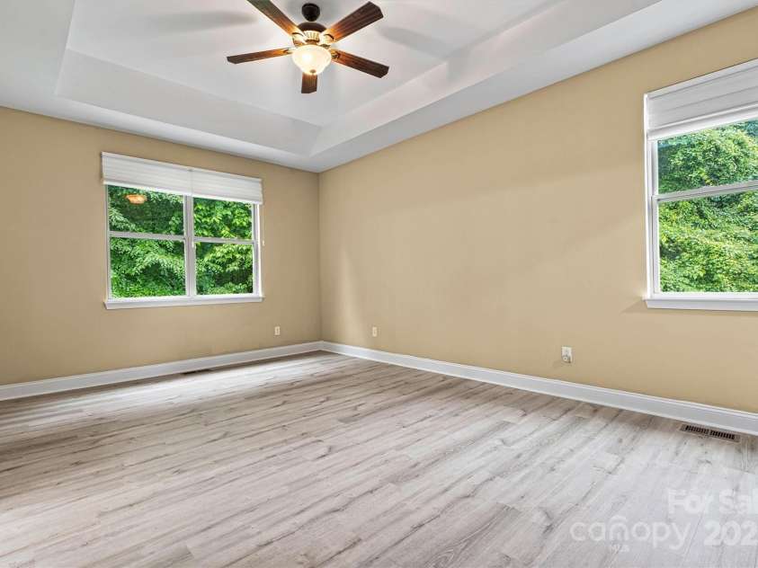 7020 Cedar Ridge Court, Mount Holly, NC 28120.  MLS# CAR4256213, YatesRealty ID 16957. Newer LVP flooring in the primary bedroom, with tray ceiling, and ceiling fan.