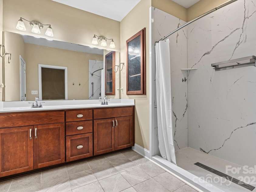 7020 Cedar Ridge Court, Mount Holly, NC 28120.  MLS# CAR4256213, YatesRealty ID 16957. There's plenty of room for both of you to get ready in the mornings in this spacious primary bath!  Double vanity sinks and huge walk in shower, installed in 2023.