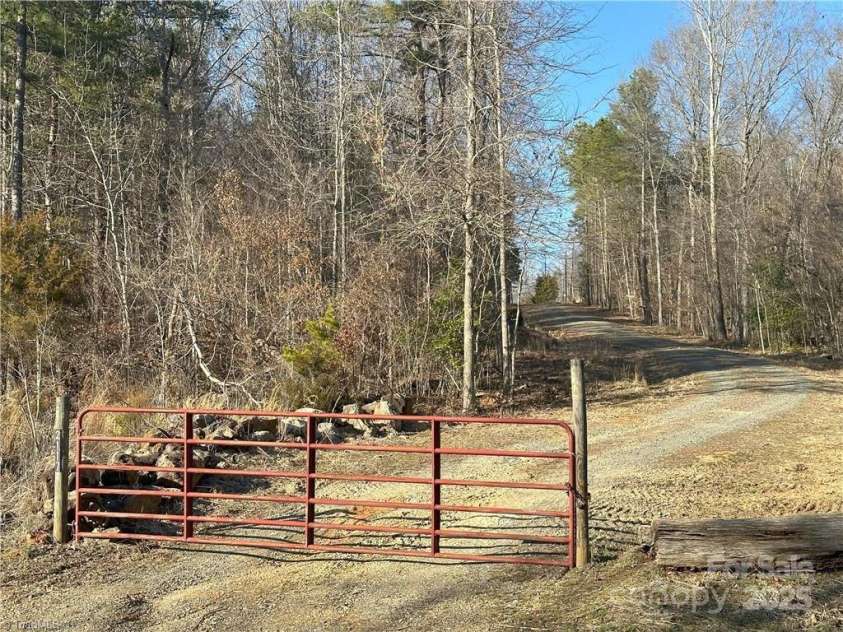 2117 Slate Mine Road, Denton, NC 27239.  MLS# CAR4220730, YatesRealty ID 17181. The locked red gate is located on Slate Mine Road.  This is a shared private road with 2 other property owners and the acreage for sale begins just after crossing under the powerlines ahead.