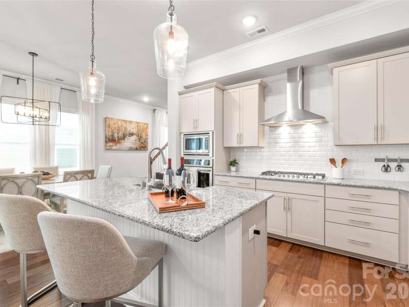 411 Belton Street, Charlotte, NC 28209.  MLS# CAR4321222, YatesRealty ID 17202. Chef’s dream kitchen with soft-close cabinets, stainless steel appliances, a 5-burner gas cooktop, subway tile backsplash, and a large center island with designer lighting.