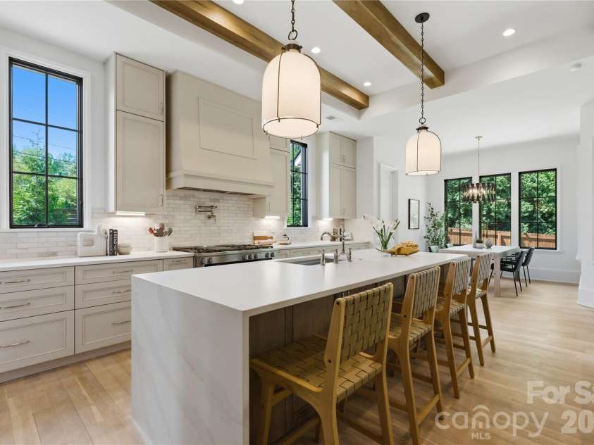 7005 Chateau Bordeaux Lane, Charlotte, NC 28270.  MLS# CAR4361151, YatesRealty ID 17330. Chef’s kitchen featuring an oversized waterfall island, custom cabinetry, professional-grade appliances, exposed wood beams, and seamless flow into main living spaces.