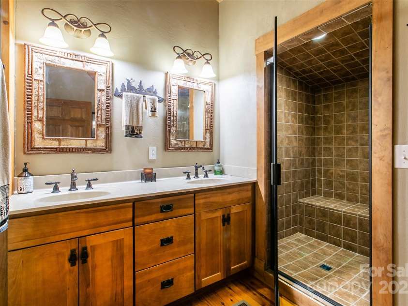 58 Great Aspen Way, Black Mountain, NC 28711.  MLS# CAR4256095, YatesRealty ID 17415. The loft bedroom bathroom has twin vanities, a large walk-in fully tiled shower with bench, and a water closet.
