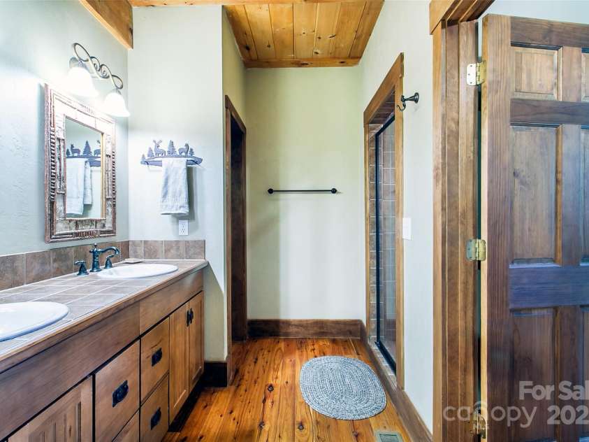 58 Great Aspen Way, Black Mountain, NC 28711.  MLS# CAR4256095, YatesRealty ID 17415. The primary bathroom has twin vanities, a water closet, linen shelves, and a gorgeous walk-in fully tiled shower with sitting bench.
