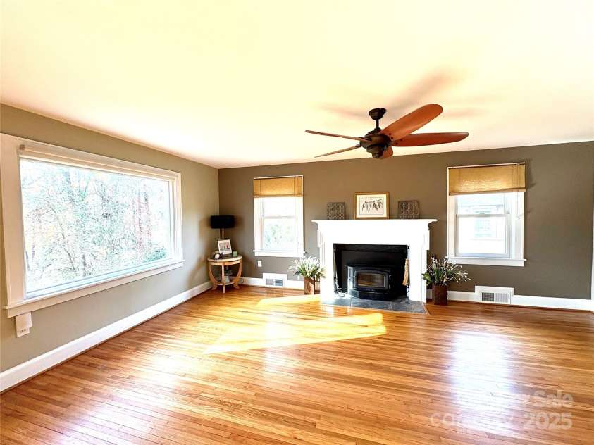 114 Broadway Avenue, Tryon, NC 28782.  MLS# CAR4322856, YatesRealty ID 17430. Large living room with a wood burning fire place insert and a large picture window that shows off those views!