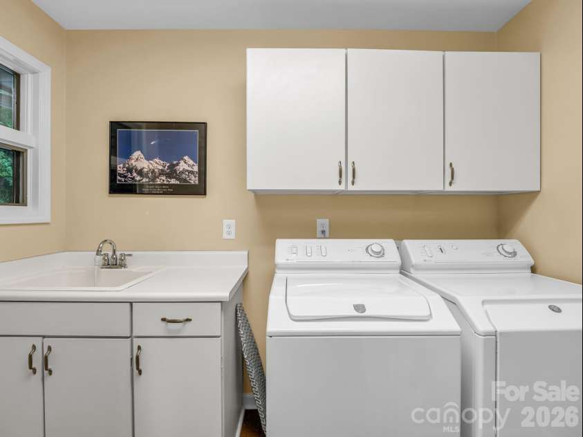 59 Agaliha Lane, Brevard, NC 28712.  MLS# CAR4392248, YatesRealty ID 1745. The spacious laundry room includes a highly convenient utility sink, a folding counter, and overhead cabinetry to keep things organized.