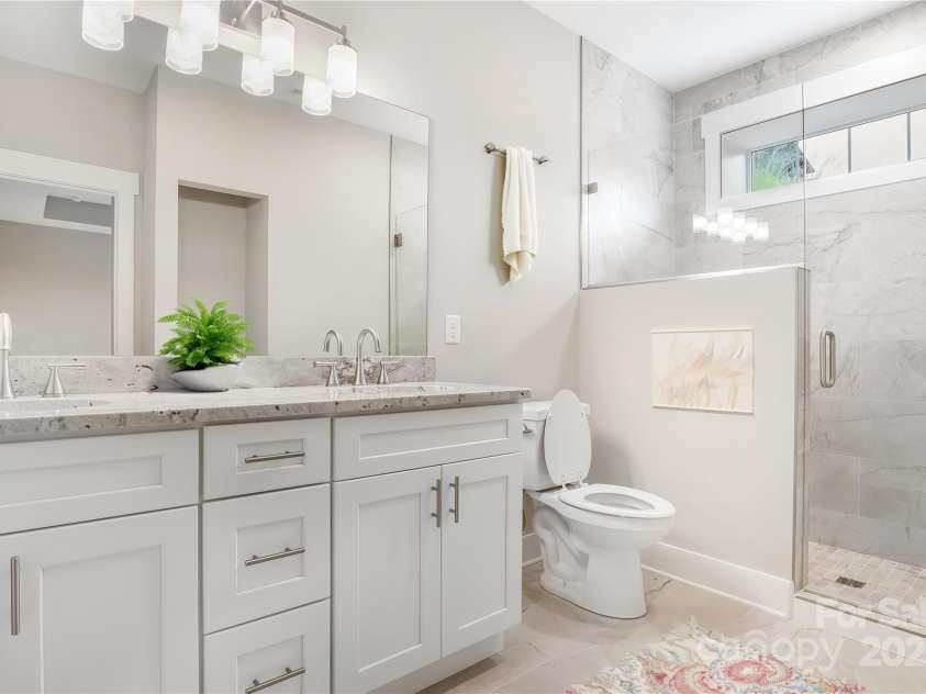 48 Creekside View Drive, Asheville, NC 28804.  MLS# CAR4046496, YatesRealty ID 17815. Primary bath with tiled shower and a bench, low profile step, dual sinks.