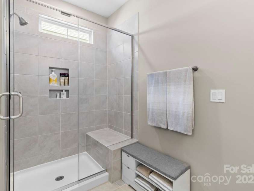 329 Secretariat Drive, Iron Station, NC 28080.  MLS# CAR4253728, YatesRealty ID 17822. An oversize shower with bench seat and transom window complement the primary bathroom