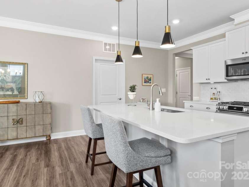 329 Secretariat Drive, Iron Station, NC 28080.  MLS# CAR4253728, YatesRealty ID 17822. Black matte pendant lighting with warm bronze accent illuminates the island in style