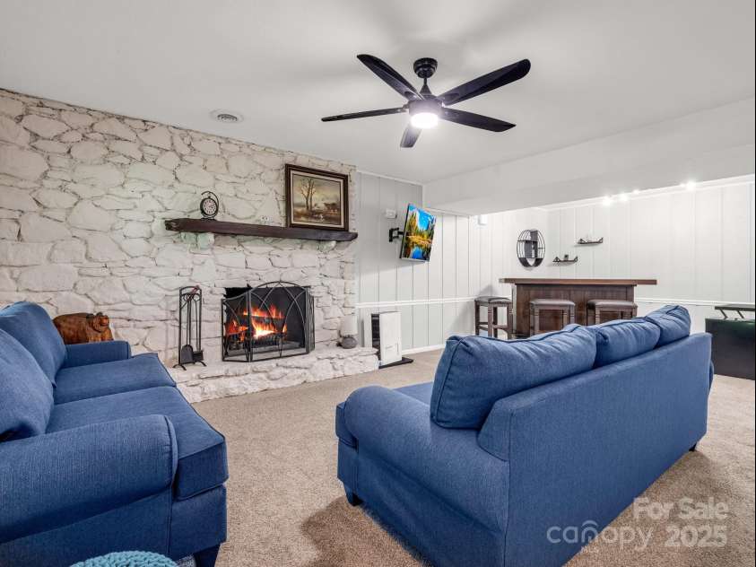 195 White Pine Drive, Lake Lure, NC 28746.  MLS# CAR4266532, YatesRealty ID 17828. Lower level in the finished walk-out basement boasts a stone fireplace, storage closet under the stairs, and access to the 1-car oversized garage.