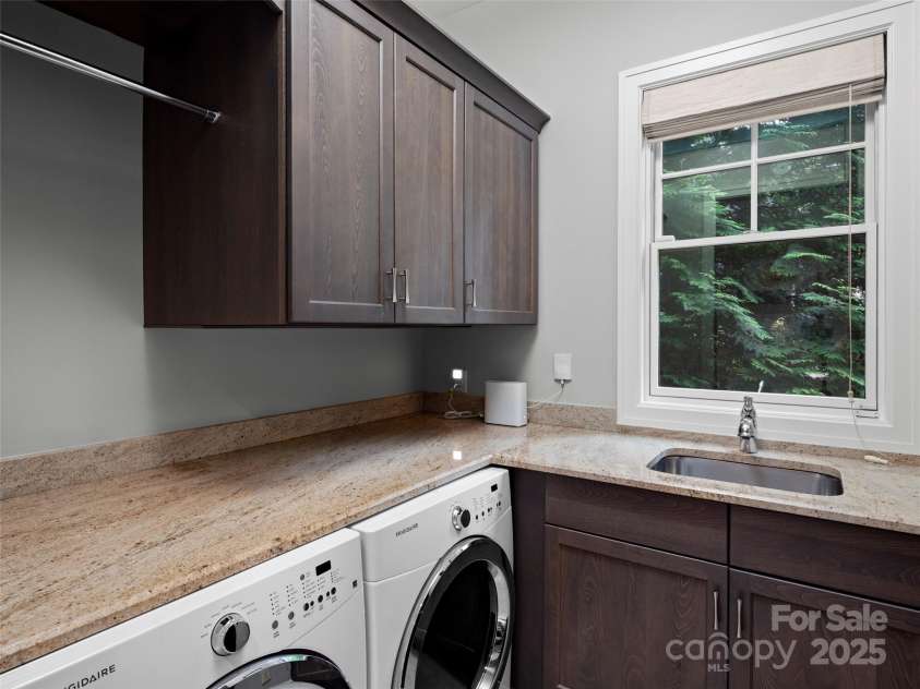 62 Running Creek Trail, Arden, NC 28704.  MLS# CAR4299725, YatesRealty ID 1785. Laundry room with granite counters for folding clothes, hanging rod for drying, a utility sink, custom cabinets and a window for ample light.