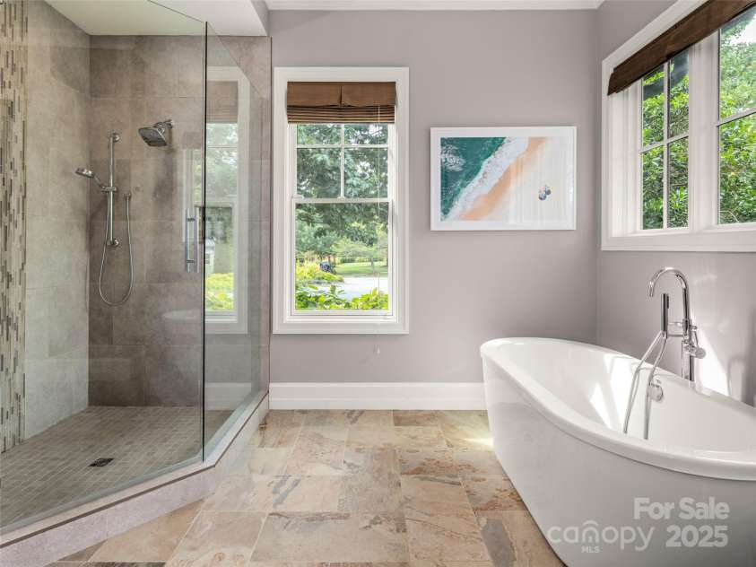 62 Running Creek Trail, Arden, NC 28704.  MLS# CAR4299725, YatesRealty ID 1785. Spa-like primary bath with soaking tub and large glass enclosed shower.  Window treatments in place for privacy.