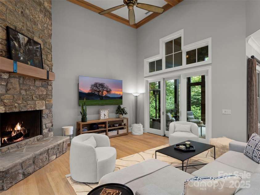 62 Running Creek Trail, Arden, NC 28704.  MLS# CAR4299725, YatesRealty ID 1785. The great room features 14' ceilings.  Natural gas fireplace includes generous stone hearth with room for sitting, a wood beam mantle and floor to ceiling stone face.   Flooring is wide plank hardwood. The porch is easil