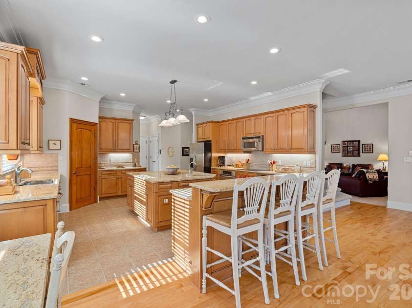 8056 Windsong Road, Denver, NC 28037.  MLS# CAR4338540, YatesRealty ID 18104. Thoughtfully designed eat-in kitchen featuring counter seating, a large island with secondary prep sink, double ovens, abundant cabinetry and counter space, walk-in pantry, and a built-in desk/work station.