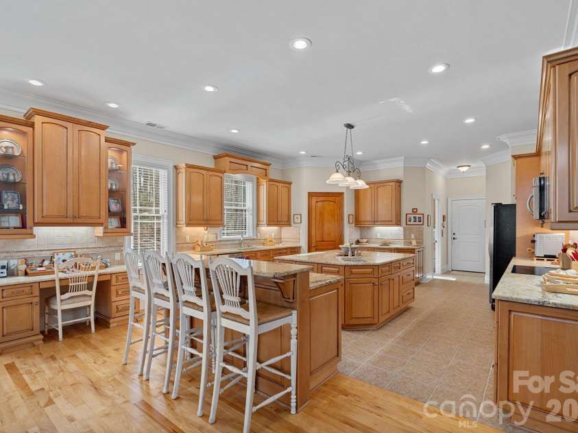 8056 Windsong Road, Denver, NC 28037.  MLS# CAR4338540, YatesRealty ID 18104. Thoughtfully designed eat-in kitchen featuring counter seating, a large island with secondary prep sink, double ovens, abundant cabinetry and counter space, walk-in pantry, and a built-in desk/work station.