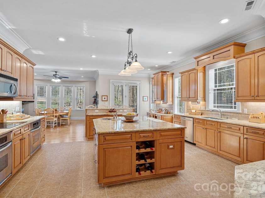 8056 Windsong Road, Denver, NC 28037.  MLS# CAR4338540, YatesRealty ID 18104. Thoughtfully designed eat-in kitchen featuring counter seating, a large island with secondary prep sink, double ovens, abundant cabinetry and counter space, walk-in pantry, and a built-in desk/work station.