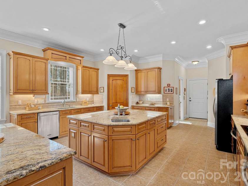 8056 Windsong Road, Denver, NC 28037.  MLS# CAR4338540, YatesRealty ID 18104. Thoughtfully designed eat-in kitchen featuring counter seating, a large island with secondary prep sink, double ovens, abundant cabinetry and counter space, walk-in pantry, and a built-in desk/work station.